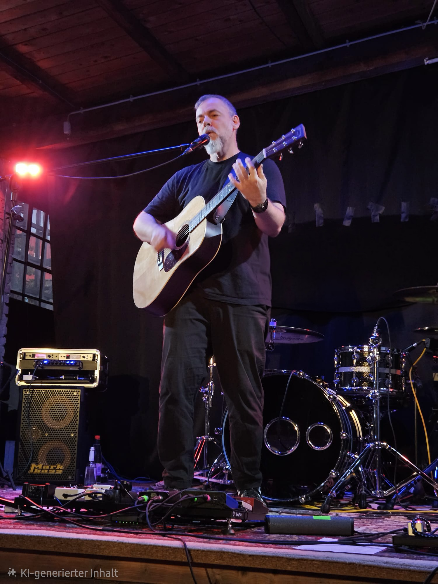 Roman Scherer spielt live mit Akustikgitarre auf einer kleinen Clubbühne